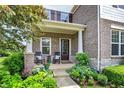 Charming front porch with rocking chairs, potted plants, and a beautifully landscaped garden at 2715 Benmore Ct, Zionsville, IN 46077