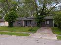 View of exterior, highlighting the home's setting amongst trees and a driveway, in a residential neighborhood at 3509 N Wittfield St, Indianapolis, IN 46235