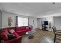 Spacious living room featuring hardwood floors, a large red couch, and a bright window for natural light at 3509 N Wittfield St, Indianapolis, IN 46235