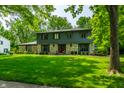 Charming two-story home featuring a stone facade, lush green lawn, and mature trees at 3715 Rolling Springs Dr, Carmel, IN 46033