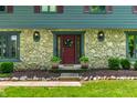 Charming front entrance featuring a stone facade, red door, and manicured landscaping at 3715 Rolling Springs Dr, Carmel, IN 46033