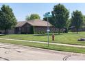 Well-maintained single-story brick home with manicured lawn, mature trees, and corner street view at 4910 Bowie Dr, Anderson, IN 46013
