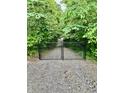 View of a secluded gravel driveway with a black gate, and surrounded by lush greenery, creating a sense of privacy at 5055 Turkey Track Rd, Martinsville, IN 46151