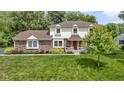 Well-maintained home exterior with lush green lawn, mature trees, and manicured landscaping at 59 Sycamore Dr, Carmel, IN 46033