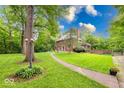 Charming brick home with manicured lawn, mature trees, and a inviting walkway to the front door and has exterior lighting at 6125 N Olney St, Indianapolis, IN 46220
