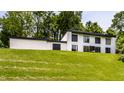 View of the home from a distance on a sunny day, highlighting the design against the green lawn and trees at 6164 Afton Crest, Indianapolis, IN 46220