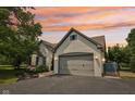 Beautiful white brick home showcasing an attached two-car garage and a serene sunset backdrop at 10444 Indian Lake N Blvd, Indianapolis, IN 46236