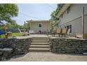 Stone retaining wall and steps up to a patio area with outdoor furniture and a shed at 1524 Northcrest Dr, Anderson, IN 46012