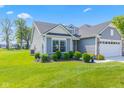 Well-maintained gray home with manicured lawn and a two-car garage is accented by verdant landscaping at 19387 Astoria Ave, Sheridan, IN 46069