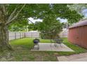 Spacious backyard featuring mature trees, a grilling area with outdoor seating, and a charming wooden fence at 1944 Union St, Columbus, IN 47201