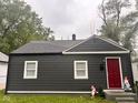 View of home with dark gray siding, white trim, and a vibrant red front door at 2954 N Drexel Ave, Indianapolis, IN 46218