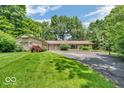 Charming home boasting a well-maintained lawn, circular driveway, and mature landscaping for added privacy at 450 W 93Rd St, Indianapolis, IN 46260