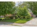A well-manicured front yard with mature trees complements this home's charming curb appeal and brick and blue siding at 5126 Hillside Ave, Indianapolis, IN 46205