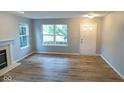 Cozy living room with fireplace, wood-look floors and neutral paint with ample natural light at 6412 Cradle River Dr, Indianapolis, IN 46221