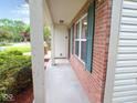 View of the covered front porch of a brick home with green shutters and vinyl siding at 6412 Cradle River Dr, Indianapolis, IN 46221