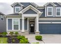 Covered entrance with stone accents, blue siding, and well maintained landscape at 6537 Seabiscuit Rd, Whitestown, IN 46075