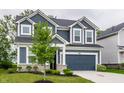 Two-story home with blue siding, a two-car garage, and landscaping at 6537 Seabiscuit Rd, Whitestown, IN 46075