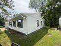 The house's exterior showcases pristine white siding, complemented by gray accents on windows, gutters, and lush greenery at 7641 E 35Th St, Indianapolis, IN 46226