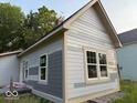 This exterior shot shows a light colored house featuring new windows and light trim at 827 W 9Th St, Anderson, IN 46016