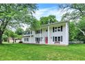 Two-story colonial with red front door, black shutters, benches, white siding and beautiful front lawn at 1000 Leisure Ln, Greenwood, IN 46142