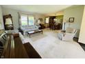 Spacious living room featuring neutral carpeting, a large window, and an adjacent dining area for easy entertaining at 1008 Whispering Trl, Greenfield, IN 46140