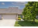 Exterior of a home with attached garage, driveway, lush lawn, and landscaping at 10668 Whippoorwill Ln, Indianapolis, IN 46231
