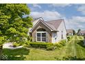 Side view of the home showcasing manicured landscaping, large window, and lush green lawn at 10668 Whippoorwill Ln, Indianapolis, IN 46231