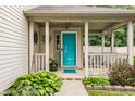 Inviting front porch featuring a vibrant turquoise door, classic columns, and decorative greenery at 1112 Halifax Ct, Indianapolis, IN 46231
