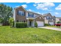 Inviting two-story home with a brick and vinyl facade, green lawn, and a convenient two-car garage, perfect for suburban living at 12322 Cool Winds W Way, Fishers, IN 46037