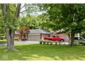 A red truck sits in front of this brick home with lush greenery, offering a suburban charm at 1345 Westwind Dr, Avon, IN 46123