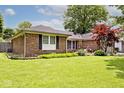 Well-kept brick home with vibrant green lawn, shrubbery, and an inviting landscape at 1345 Westwind Dr, Avon, IN 46123