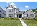 Charming two-story home with gray siding, black shutters, and a beautifully landscaped front yard with colorful flowers at 14234 Community Dr, Carmel, IN 46033