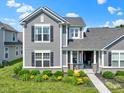 Charming gray home with black shutters and a covered porch, enhanced by vibrant flowers and manicured landscaping at 14234 Community Dr, Carmel, IN 46033