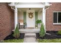 Inviting front porch with a decorative wreath, chair, and charming details that add curb appeal at 14492 Cotswold Ln, Carmel, IN 46033