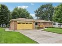 Single-story brick home featuring a lush lawn, driveway, and a cheerful yellow garage door at 230 Love Ave, Greenwood, IN 46142
