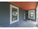 Close-up of a front porch with a storm door, two windows and a painted, wooden ceiling at 2860 Winthrop Ave, Indianapolis, IN 46205