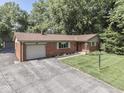 Lovely single-story brick home featuring an attached garage, beautiful landscaping, and a paved driveway at 343 E Waterbury Rd, Indianapolis, IN 46227