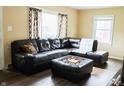 Comfortable living room featuring a large, inviting leather sectional and a plush ottoman on wood floors at 3616 N Dearborn St, Indianapolis, IN 46218