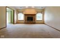 Bright living room featuring a classic brick fireplace, neutral carpeting, and abundant natural light at 413 Blue Spring Dr, Indianapolis, IN 46239
