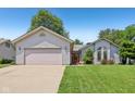 Inviting single-story home with attached garage, lush lawn, and delightful landscaping at 430 Oakbrook Dr, Columbus, IN 47201