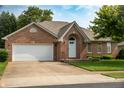 Charming brick home with a well-manicured lawn, an arched entryway, and an attached two-car garage at 5032 Monticello Dr, Columbus, IN 47203