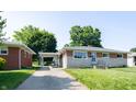 Inviting single-story home with brick and stone accents, a well-kept lawn, and a convenient carport at 5609 Meadowood Dr, Indianapolis, IN 46224