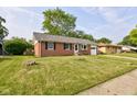 A charming red brick home features a lush green lawn and mature trees at 5923 W 29Th Pl, Indianapolis, IN 46224