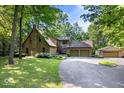 Picturesque stone home with lush landscaping, a two-car garage, a small outbuilding, and a circular driveway at 6975 Milhouse Rd, Indianapolis, IN 46221