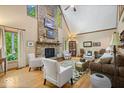 Spacious living room with a stone fireplace, vaulted ceiling, hardwood floors, and multiple seating areas at 6975 Milhouse Rd, Indianapolis, IN 46221