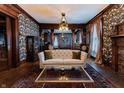 Elegantly decorated living room with a tufted sofa, beautiful wallpaper, and period lighting at 825 E Washington St, Muncie, IN 47305