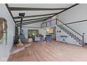 Spacious living room with wood floors, exposed ceiling beams, a wood-burning fireplace and a staircase to an upper level at 8435 Hilltop Ln, Martinsville, IN 46151