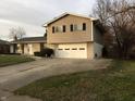 Side view of split-level home with beige siding, showcasing a two-car garage and concrete driveway at 9016 Neptune Dr, Indianapolis, IN 46229