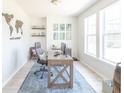 Bright home office featuring a wooden desk, blue rug, and natural light from large windows at 9248 Hawley Dr, Indianapolis, IN 46216