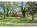 Charming two-story brick home surrounded by mature trees and a green lawn at 9256 Colgate St, Indianapolis, IN 46268